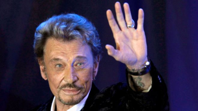 FILE PHOTO: French singer Johnny Hallyday waves to fans attending a ceremony to promote his new album "Jamais seul" (Never alone) at the Virgin Megastore in Paris